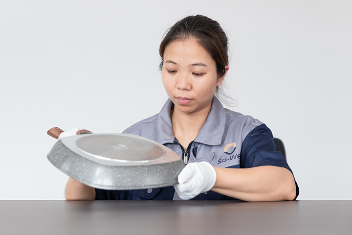 a worker inspects casting aluminum skillet