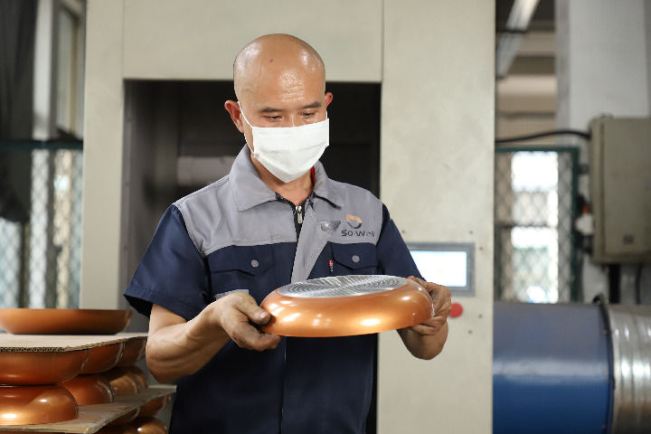 a dedicated worker is examining aluminum frying pan